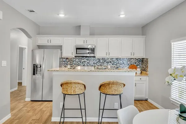 a kitchen with stainless steel appliances a sink a stove a refrigerator cabinets and a dining table