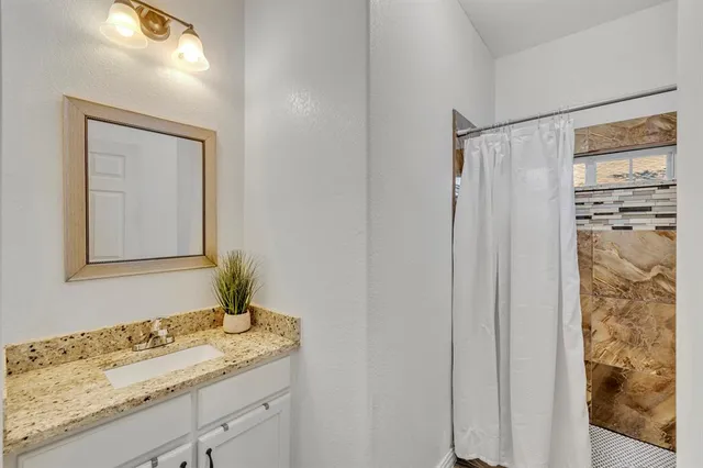 a bathroom with a granite countertop sink and a mirror