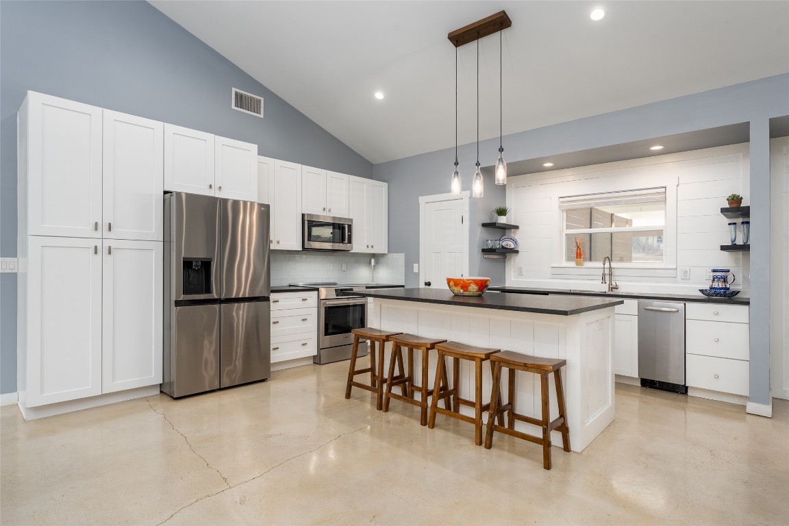 33 Deer Ridge Road Wimberley, TX 78676 - Photo 12 of 40 a kitchen with stainless steel appliances granite countertop a refrigerator a sink dishwasher a stove and white cabinets with wooden floor