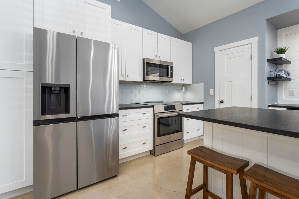 33 Deer Ridge Road Wimberley, TX 78676 - Photo 15 of 40 a kitchen with granite countertop a refrigerator stove and microwave