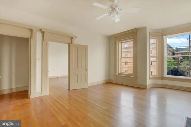 an empty room with wooden floor fireplace and windows