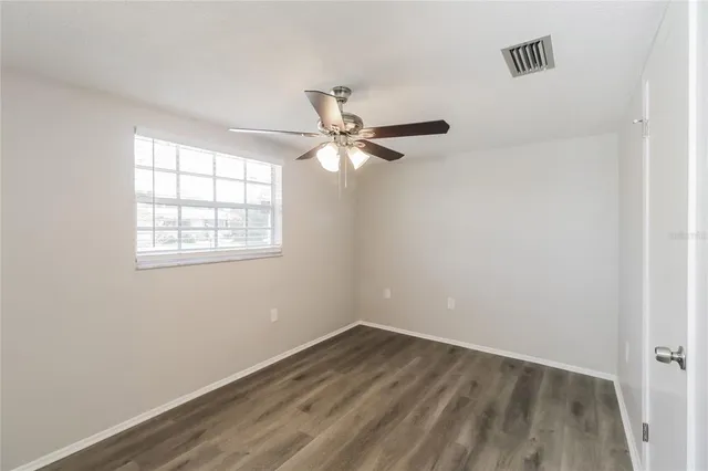 an empty room with a window and a fan