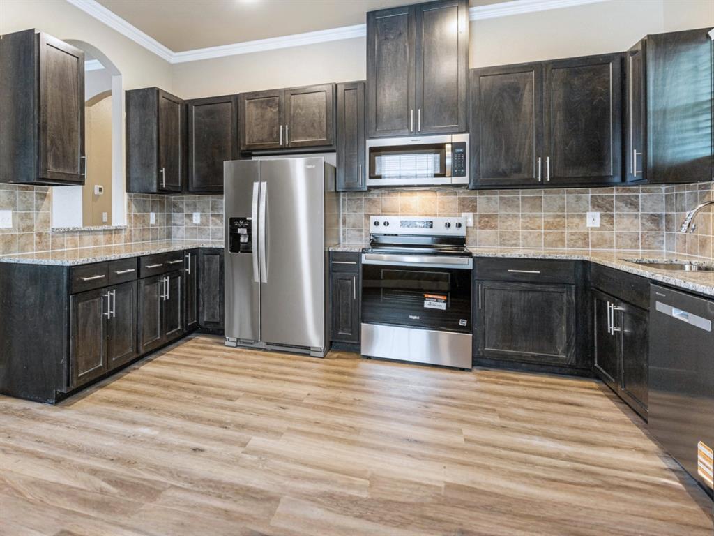 413 Henderson Street Bonham, TX 75418 - Photo 7 of 27 a kitchen with stainless steel appliances granite countertop a refrigerator and a stove top oven