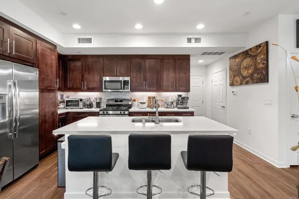 a kitchen with stainless steel appliances granite countertop a sink a stove a refrigerator cabinets and chairs