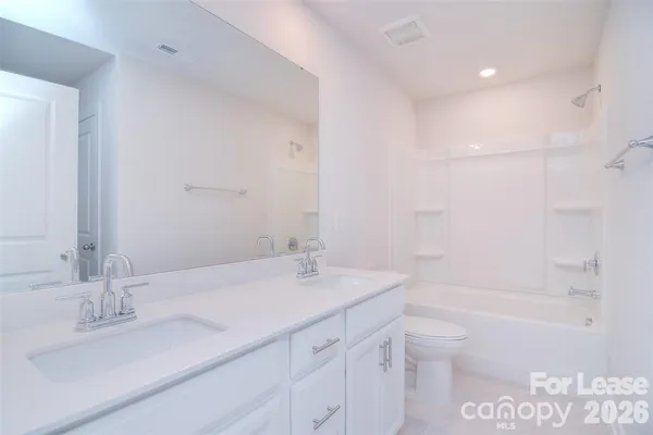 a bathroom with a granite countertop sink a toilet and shower