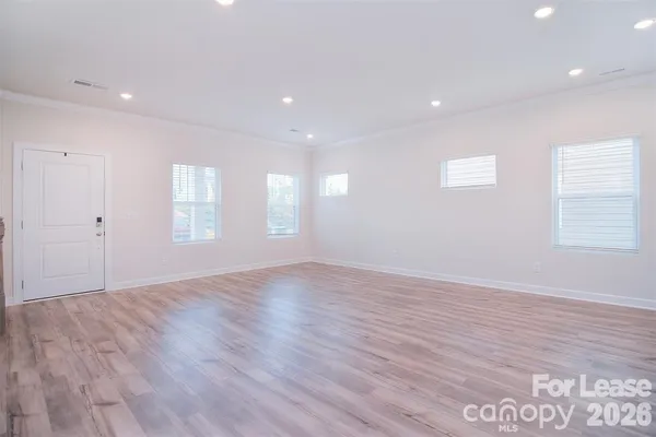 a view of an empty room with wooden floor and window