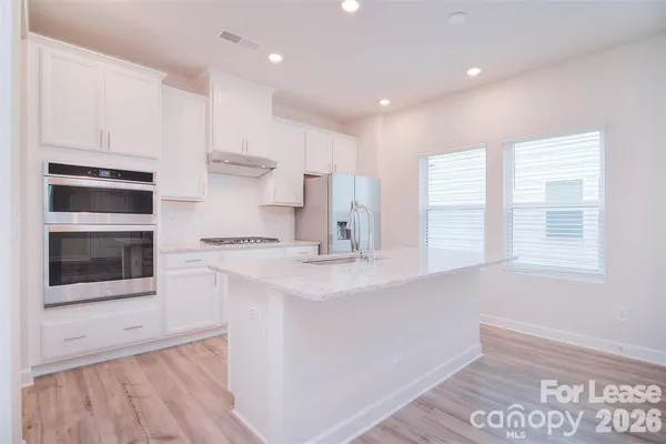 a kitchen with kitchen island a sink stainless steel appliances and cabinets