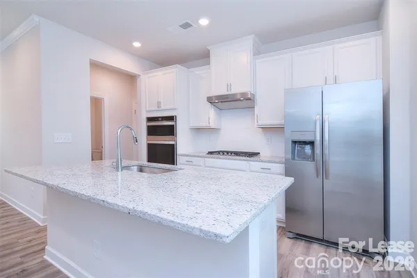 a kitchen with kitchen island granite countertop a sink and refrigerator