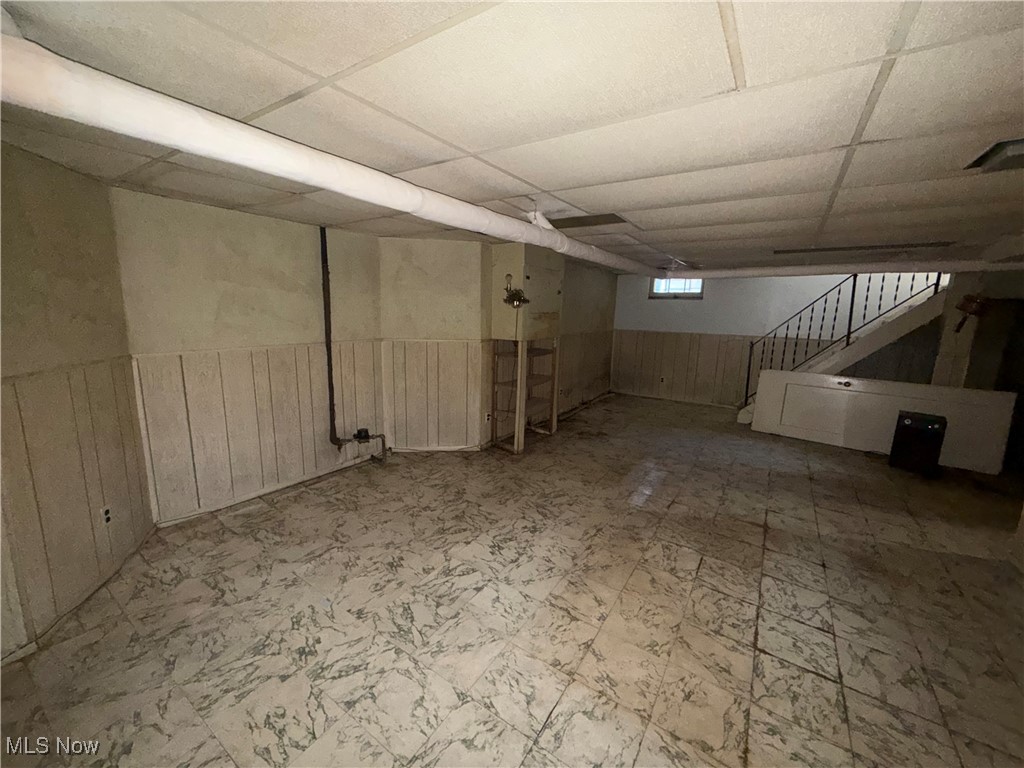 1979 Staunton Road Cleveland, OH 44118 - Photo 31 of 37 Basement featuring wooden walls, a wainscoted wall, a paneled ceiling, stairs, and tile patterned floors