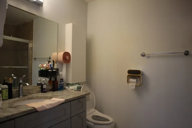 a bathroom with a granite countertop sink a toilet and mirror