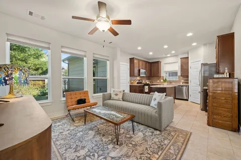 a living room with furniture kitchen view and a large window