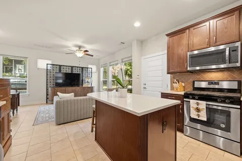a kitchen with kitchen island granite countertop a sink cabinets stainless steel appliances and a window