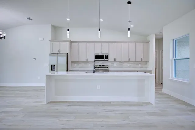 a view of kitchen with stainless steel appliances granite countertop cabinets and wooden floor
