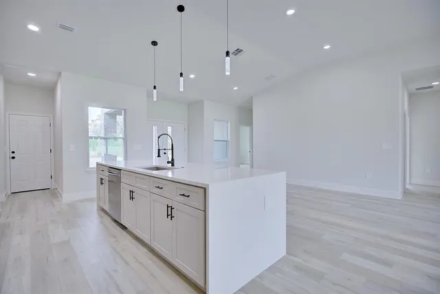 a large white kitchen with a large island oven a sink with stainless steel appliances