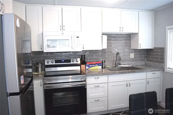 a kitchen with granite countertop a sink stainless steel appliances and cabinets