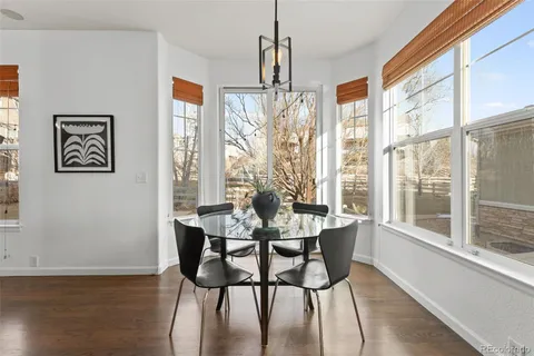 a dining room with wooden floor a chandelier a glass table and chairs