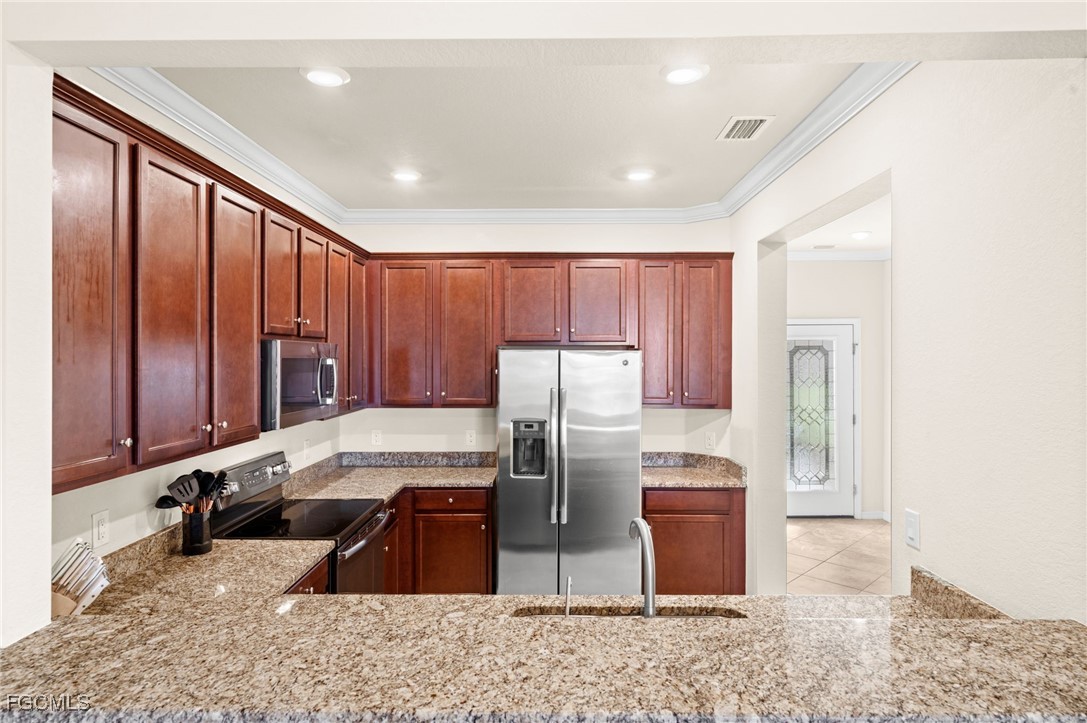 10173 Via Colomba Circle Fort Myers, FL 33966 - Photo 10 of 50 a kitchen with stainless steel appliances granite countertop a refrigerator a stove and a sink with wooden cabinets