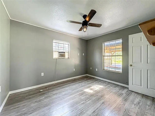 a view of empty room with wooden floor and fan