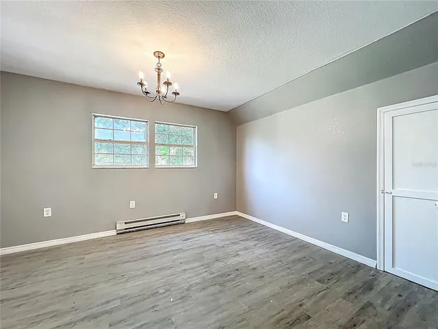 an empty room with wooden floor chandelier and windows