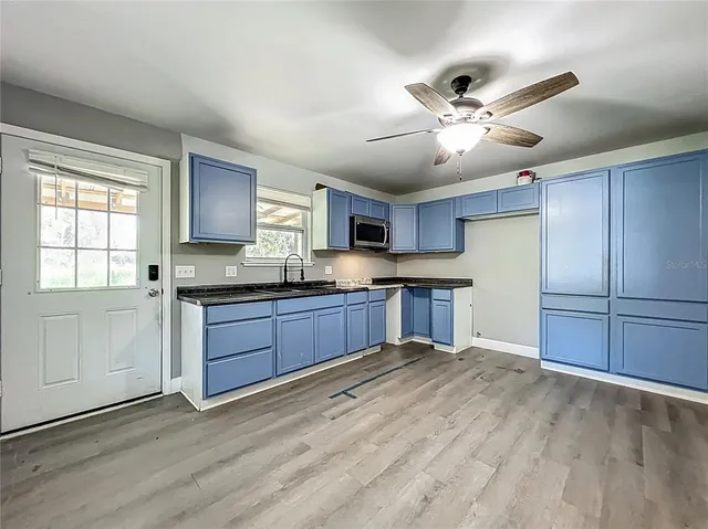 a kitchen with stainless steel appliances kitchen island granite countertop a refrigerator a sink dishwasher a stove with wooden cabinets and floor
