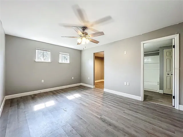 an empty room with wooden floor and ceiling fan