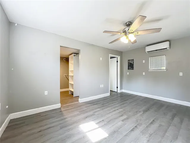 a view of an empty room with wooden floor and a ceiling fan