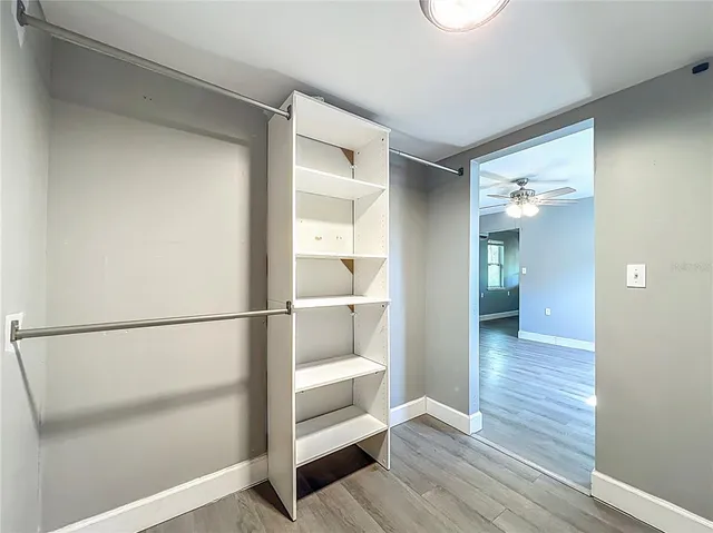 a view of a hallway with wooden floor and cabinet