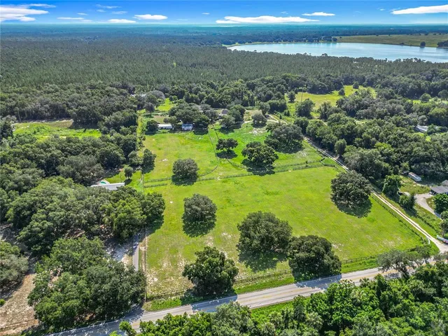 an aerial view of residential houses with outdoor space and trees