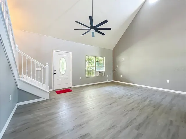 an empty room with ceiling fan and windows