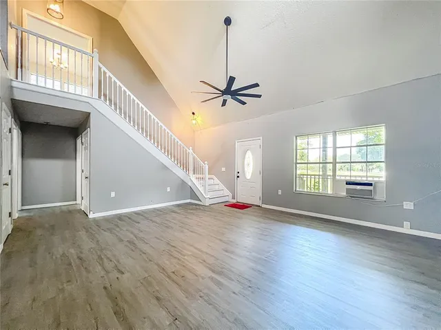 a view of an empty room with a window and wooden floor
