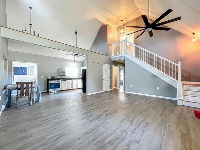 a view of a livingroom with furniture wooden floor a ceiling fan and windows