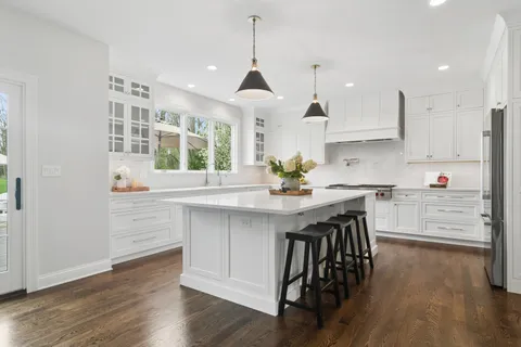 a kitchen with stainless steel appliances kitchen island granite countertop a wooden floor and white cabinets