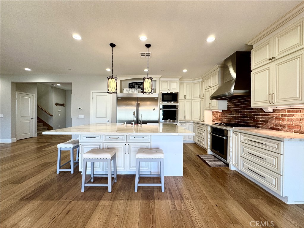 17841 Grapevine Lane San Bernardino, CA 92407 - Photo 17 of 63 a kitchen with stainless steel appliances kitchen island granite countertop a stove a sink dishwasher and a dining table with wooden floor