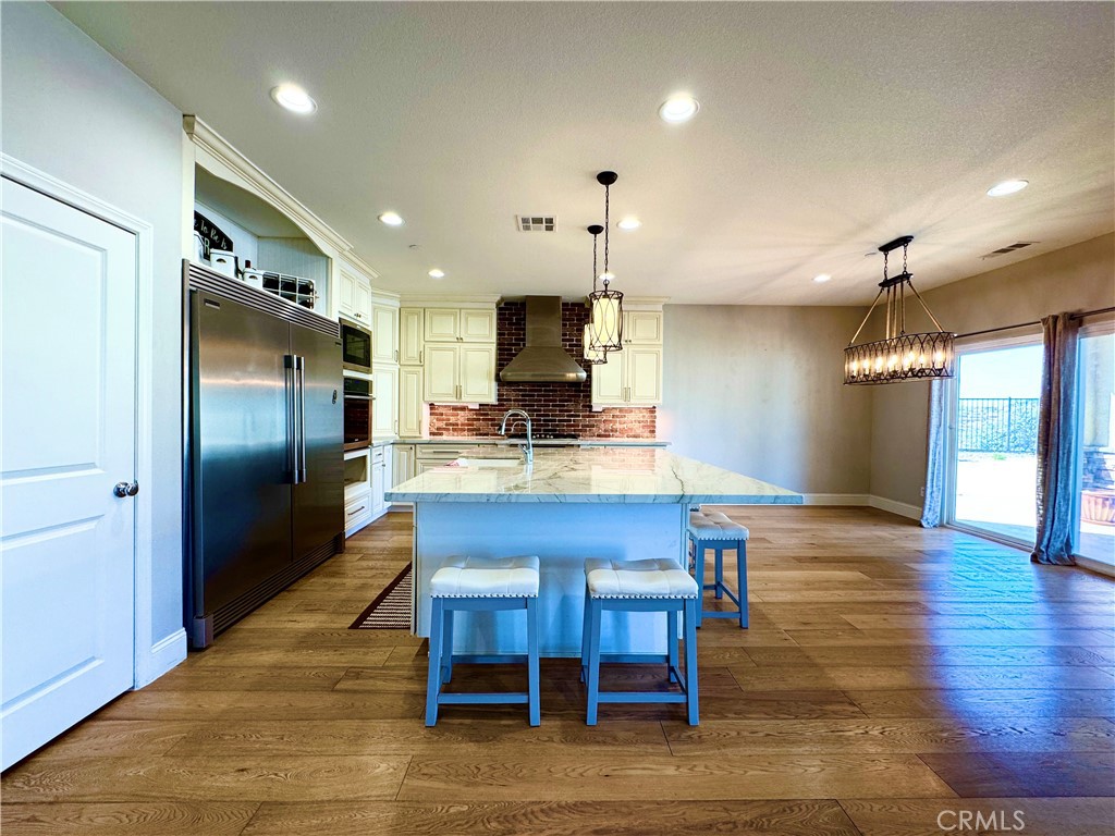 17841 Grapevine Lane San Bernardino, CA 92407 - Photo 18 of 63 a kitchen with stainless steel appliances granite countertop a refrigerator a oven a stove and a dining table with wooden floor
