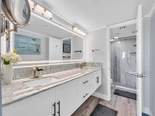 a bathroom with a granite countertop sink a mirror and a shower