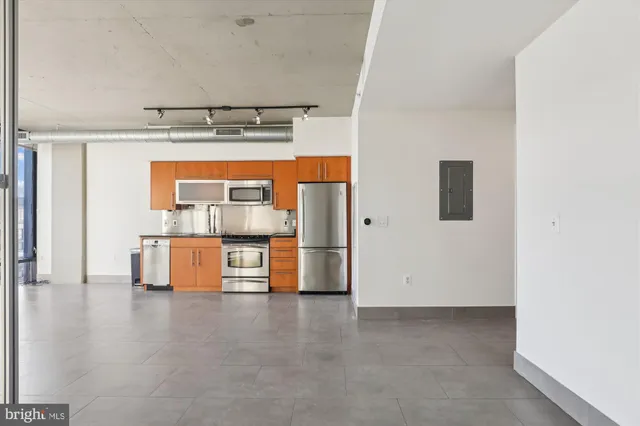 a living room with stainless steel appliances furniture and a kitchen view