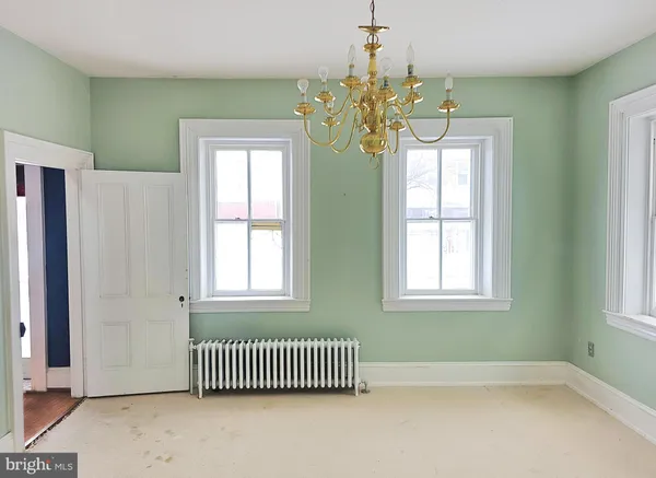 an empty room with wooden floor chandelier and windows