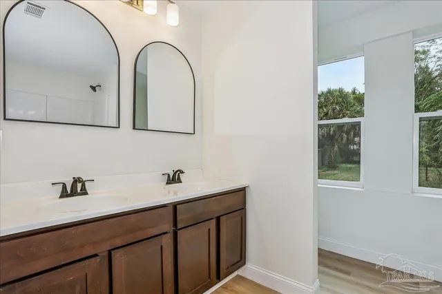an empty room with wooden floor chandelier fan and windows