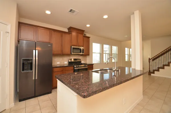 a kitchen with stainless steel appliances granite countertop a refrigerator a sink a stove and cabinets