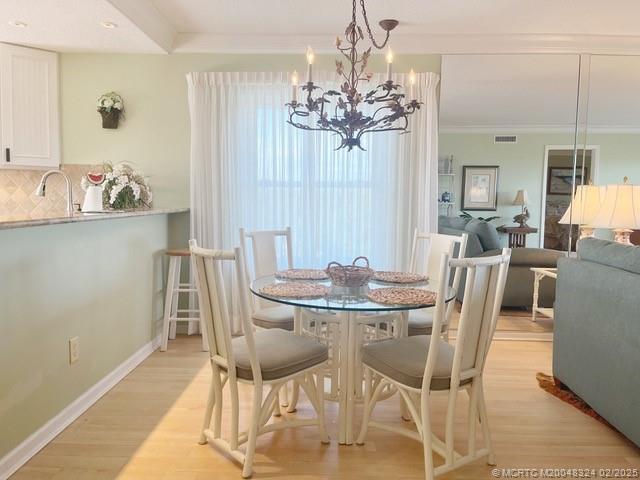 2641 Northeast Ocean Boulevard, Unit 201 Stuart, FL 34996 - Photo 18 of 34 a view of a dining room with furniture a chandelier and wooden floor
