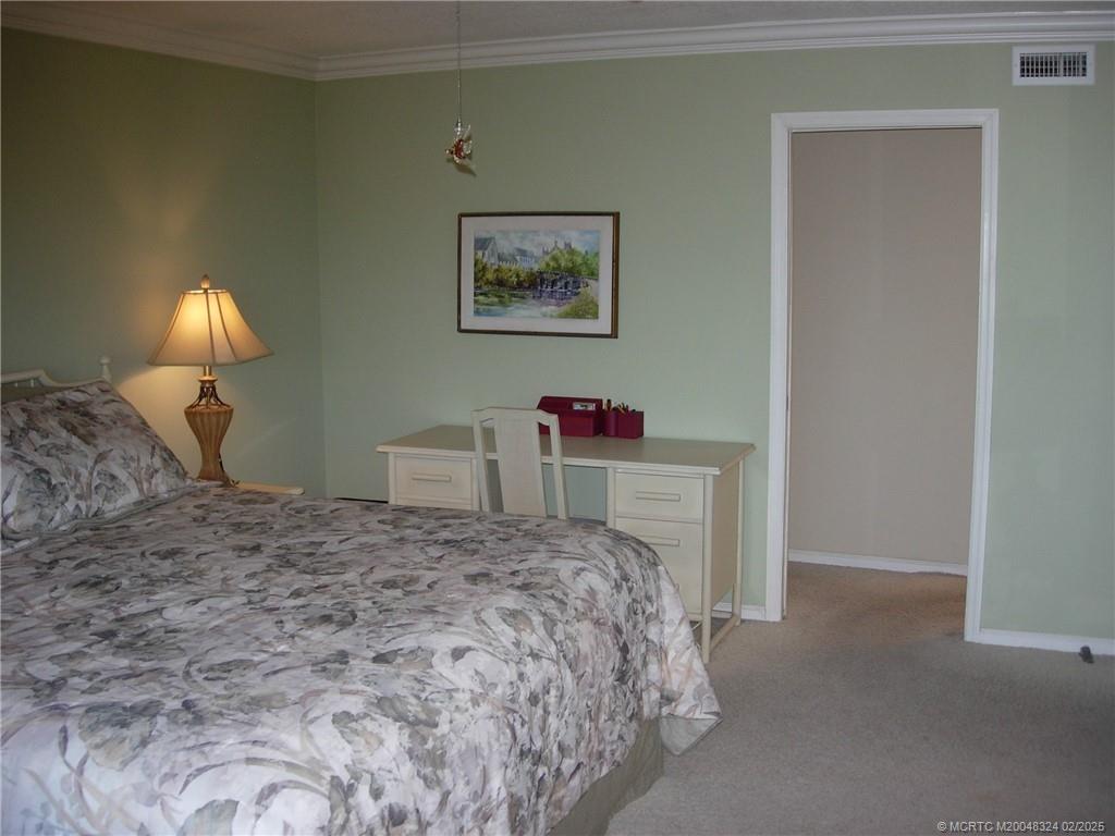 2641 Northeast Ocean Boulevard, Unit 201 Stuart, FL 34996 - Photo 10 of 34 a bedroom with a bed and a chandelier