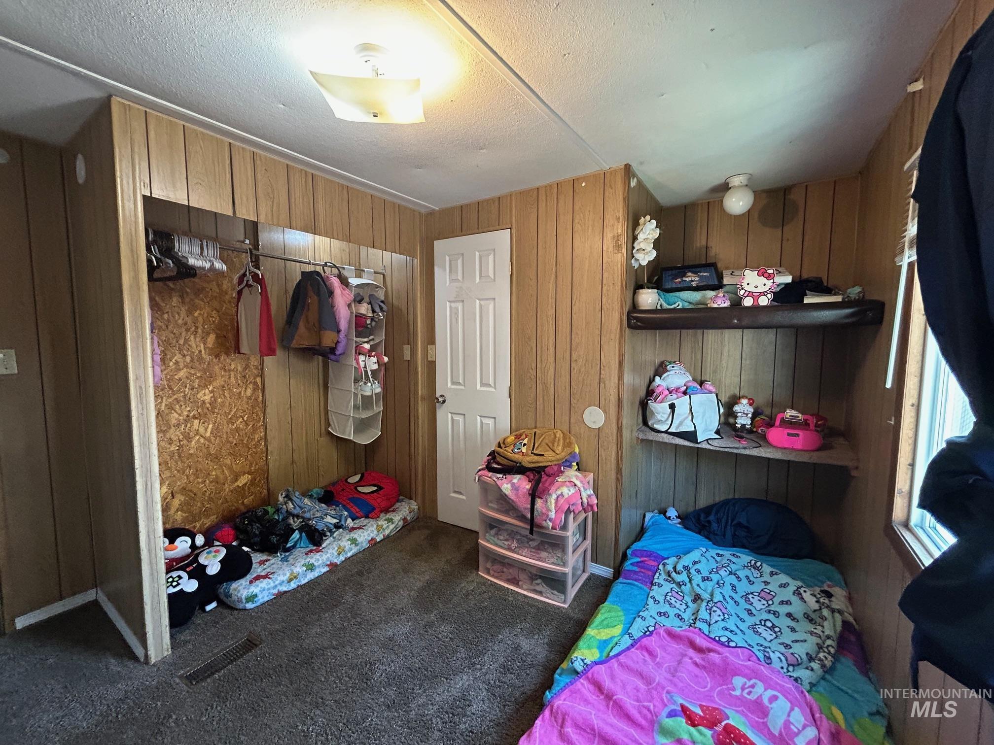 1383 Fair Street, Unit 5 Clarkston, WA 99403 - Photo 15 of 16 Bedroom with carpet flooring, wood walls, and a textured ceiling