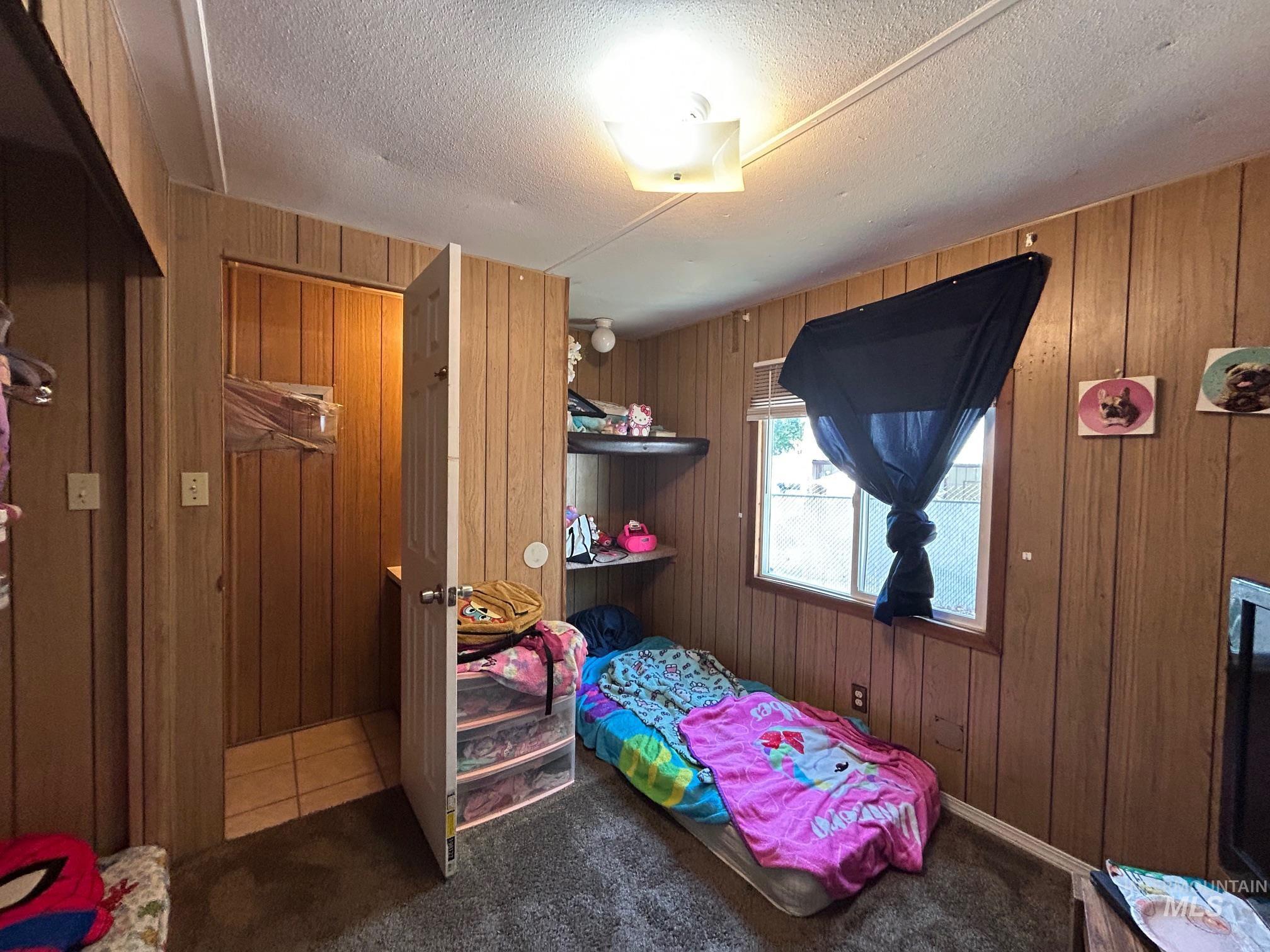 1383 Fair Street, Unit 5 Clarkston, WA 99403 - Photo 16 of 16 Bedroom featuring wood walls, carpet flooring, and a textured ceiling