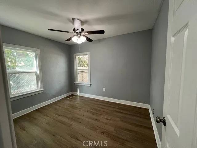 an empty room with wooden floor fan and windows