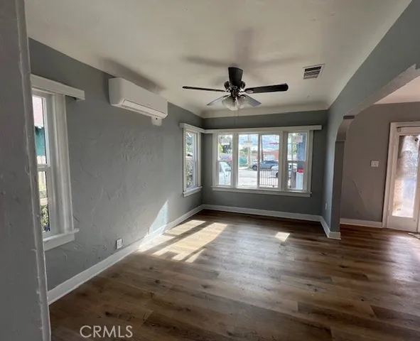a view of an empty room with window and wooden floor