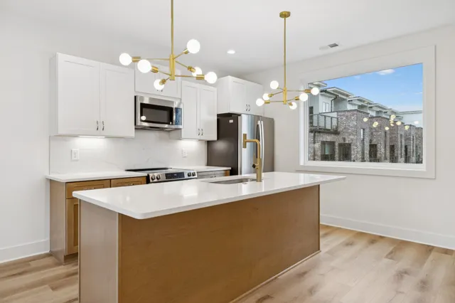 a kitchen with kitchen island a counter space a sink appliances and cabinets
