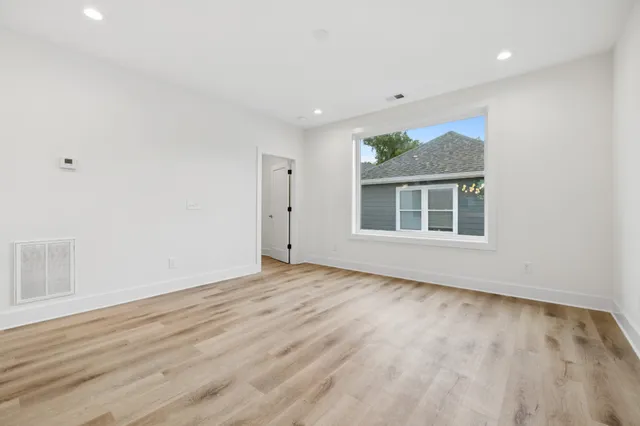a view of an empty room with wooden floor and a window