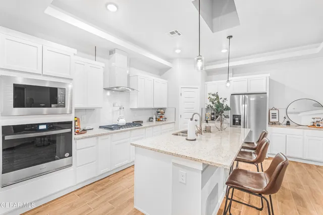 a kitchen with stainless steel appliances a stove a sink a oven a dining table and chairs