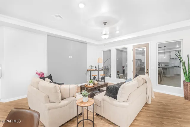 a living room with furniture kitchen view and a wooden floor
