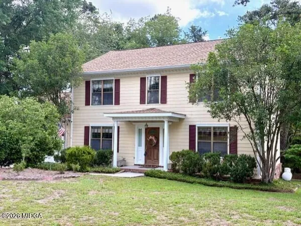 a front view of a house with a yard and trees